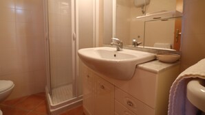 Een badkamer met een douche, wastafel en toilet.
