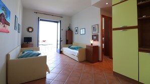 Een kamer met een bed, een bank, een kast en een televisie.