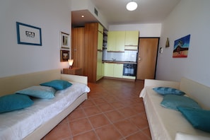 Une chambre avec deux lits, un coin cuisine et un espace repas.