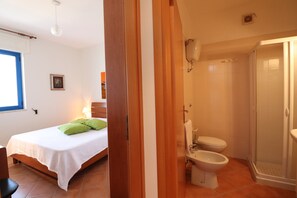 Une chambre à coucher avec un lit, une table de chevet et une fenêtre.