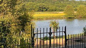 A river with a fence in the foreground and a forested hill in the background. - Gite La Maison du Passeur (Availles-Limouzine)
