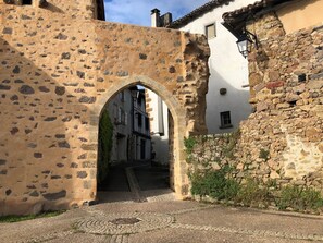 An arched stone gateway leading to a narrow street with cobblestone pavement. - Gite La Maison du Passeur (Availles-Limouzine)