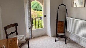 A room with a door leading to a balcony, a wooden chair, a radiator, and a framed picture on the wall. - Gite La Maison du Passeur (Availles-Limouzine)