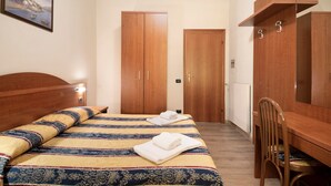 Un dormitorio con cama, armario de madera y escritorio con silla.
