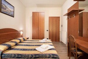 A bedroom with a bed, wooden wardrobe, and a desk with a chair.