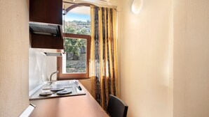 Una cocina pequeña con ventana, un lavamanos y una estufa.