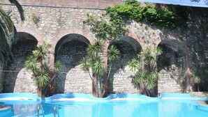 Una piscina con arcos de piedra y palmeras.