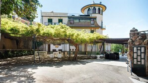 En innergård med en pergola, utomhusmöbler och en byggnad med ett torn.