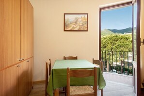 A dining area with a table, chairs, and a painting on the wall.