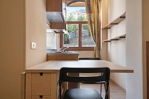 Eine Küche mit Holzausziehtisch, einem schwarzen Stuhl und einem Fenster mit Vorhängen.