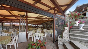 Un espace extérieur aménagé avec des tables et des chaises, un mur en pierre et un escalier orné de jardinières.