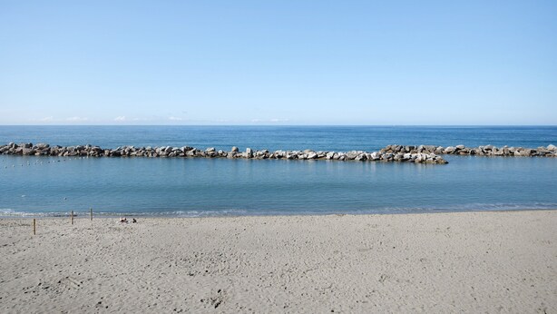 Une plage avec une digue rocheuse et une eau calme.