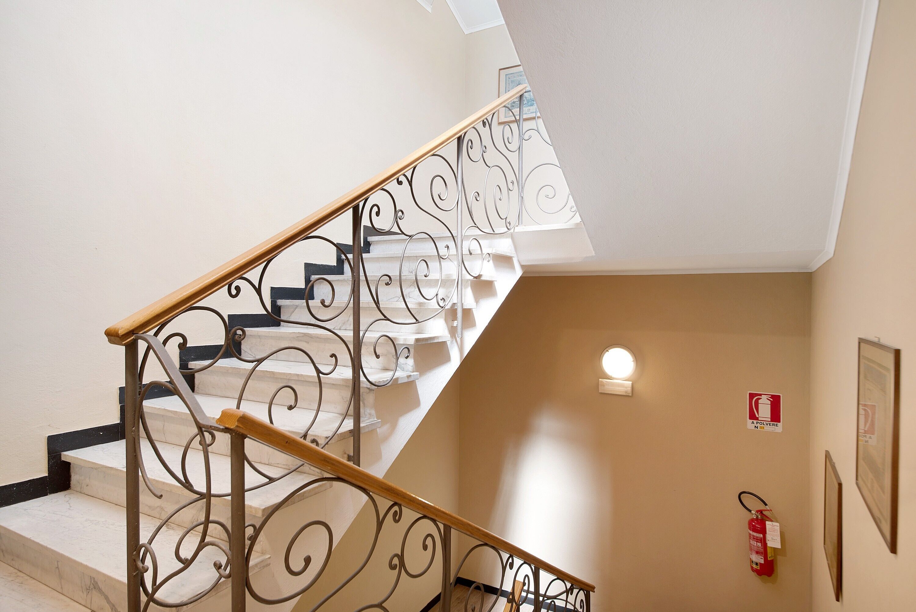 Eine Treppe mit aufwendiger Metallreling und einer Holzhandläufe, die zu einer oberen Etage führt.