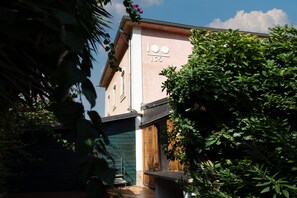 Un edificio con los números '100' y '105' en su fachada, rodeado de vegetación.