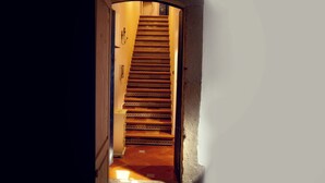 Eine Treppe führt zu einem Raum, in dem sich links eine Tür und rechts eine Wand befindet.