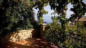 Ein Balkon mit Meerblick, umgeben von üppigem Grün und einem Fliesenboden.
