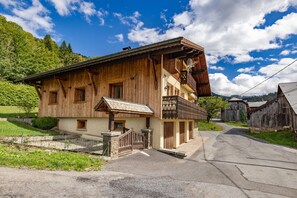 Un bĂątiment en bois dotĂ© dâun balcon, dâun petit porche et dâun mur en pierre.