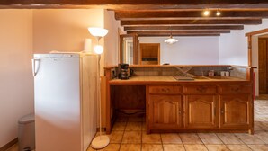 Eine Küche mit Holzschränken, einer Arbeitsplatte, einem Kühlschrank und einer Kaffeemaschine.