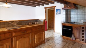 Eine Küche mit Holzausbau, einer Arbeitsplatte, einer Pendelleuchte und einer gefliesten Spritzschutzwand.