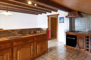 A kitchen with wooden cabinets, a countertop, a hanging light fixture, and a tiled backsplash.