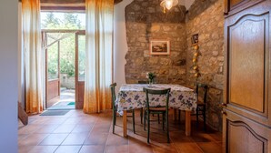 Un coin repas avec une table dressée pour quatre personnes, un mur en pierre et une porte en bois.