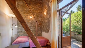 Une chambre avec un plafond en pierre, un cadre de lit en bois, une table de chevet et une fenêtre avec des rideaux.