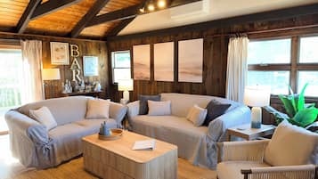 Ein gemütliches Wohnzimmer mit Holzbalkendecke, einer Sofagarnitur, einem Couchtisch und einer Bar mit einer Lampe und dekorativen Gegenständen.
