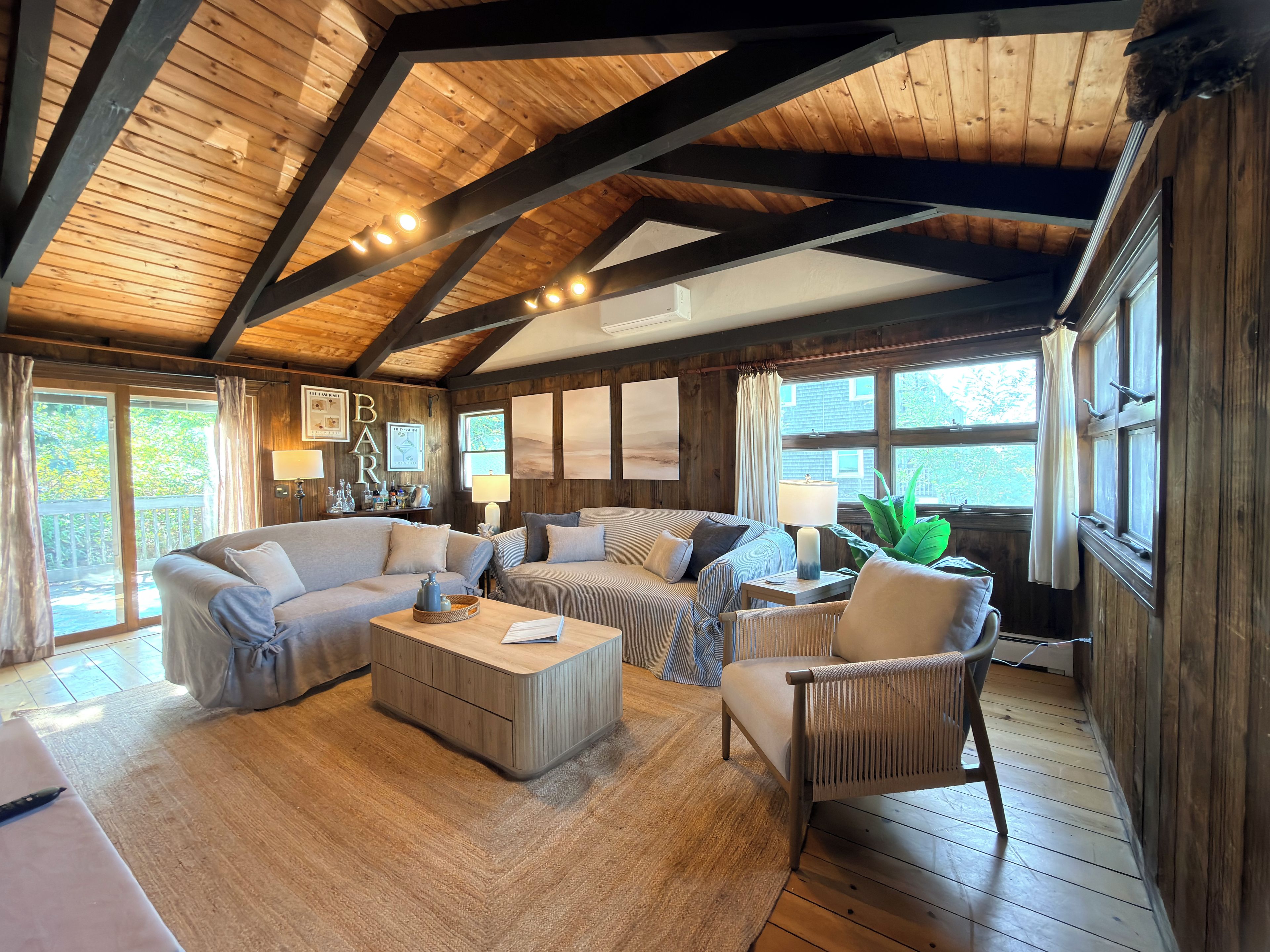 A cozy room with a wooden ceiling, a sofa set, a coffee table, and a chair.