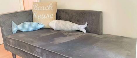 Un canapé gris agrémenté de trois coussins décoratifs, dont l’un porte un motif textuel.