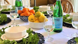 A table set with bowls of fruit, glasses, and bottles of Grinno mineral water. - Sand Bar-Dog Friendly on Cooks Brook Beach (Eastham)