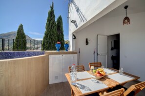 A balcony with a view of trees and a mountain, a table with chairs, and a small kitchen area. - Holiday Home Casa Almoraima with Pool & Open Terrace (Gaucin)