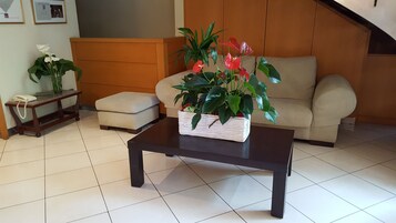 A living room with a sofa, a coffee table, a telephone, and a plant on the coffee table.