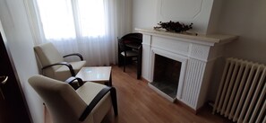 Una habitación con chimenea, una mesa, dos sillas y un radiador.