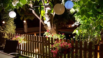 A wooden fence with a garden area, including flowers and a tree.