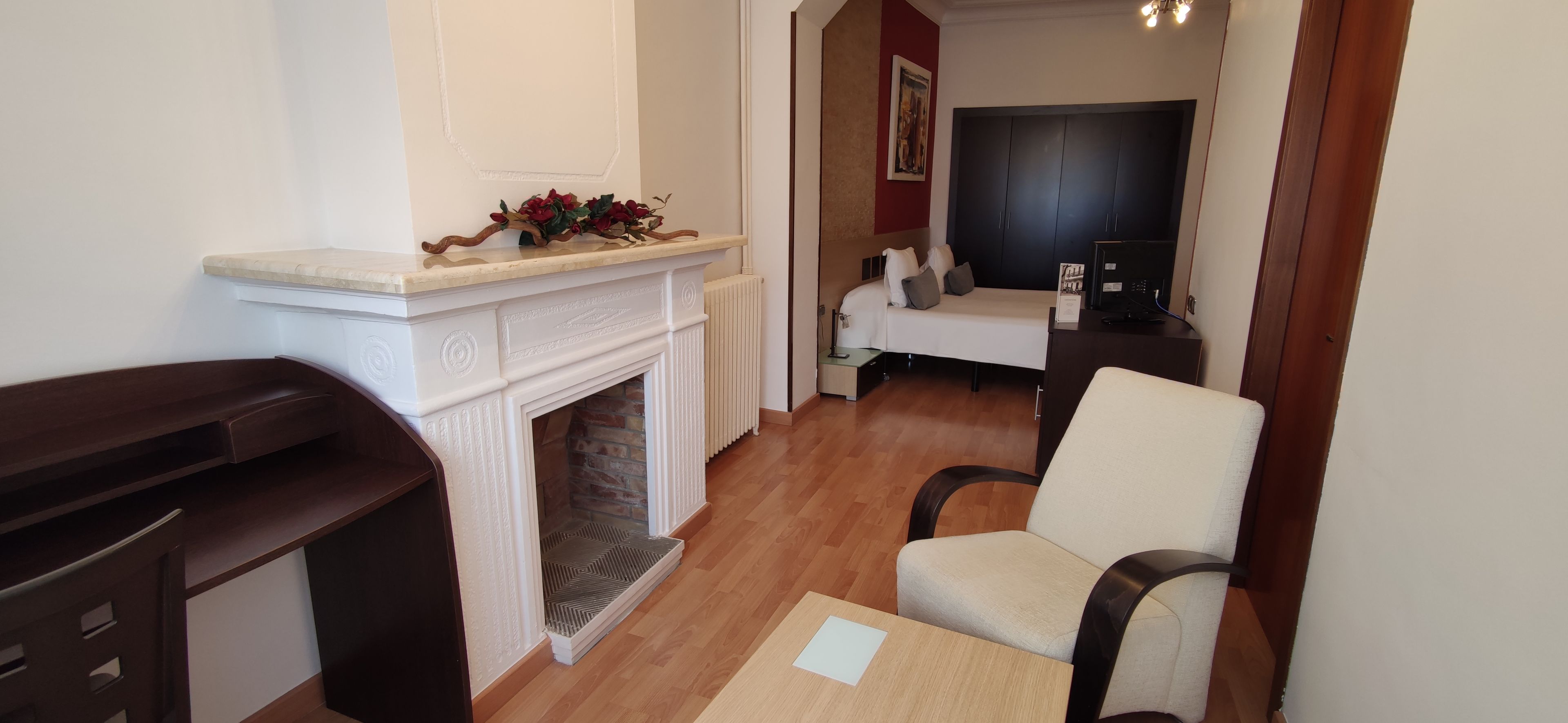 A room with a fireplace, a white sofa, a wooden chair, and a small table with a placemat.