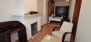 Een kamer met een open haard, een witte bank, een houten stoel en een klein tafeltje met een placemat.