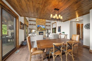 Uma sala de estar ampla com teto de madeira, lareira e mesa de jantar com cadeiras.