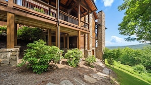A wooden cabin with a stone chimney, a balcony, and a view of the surrounding landscape. - Breezeway Lodge at Eagles Nest - hot tub, huge views, all Suite style rooms, close to tennis (Banner Elk)