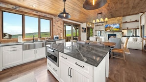 A spacious kitchen with a large island, wooden ceiling, and a stone fireplace. - Breezeway Lodge at Eagles Nest - hot tub, huge views, all Suite style rooms, close to tennis (Banner Elk)
