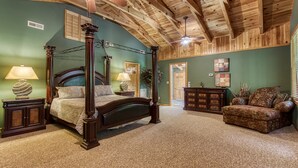 Un lit à baldaquin avec une tête de lit en bois, deux tables de chevet avec des lampes, une commode en bois foncé et un canapé à motifs.