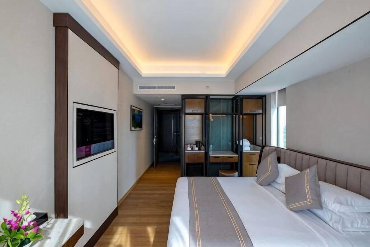 A hotel room with a bed, bedside table, and a view of the hallway.