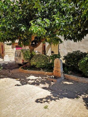 A paved area with a tree, a parked vehicle, and a stone structure. - Gut Ausgestattetes Ferienhaus in Dörflicher Lage mit Tollem Ausblick (Vendres)