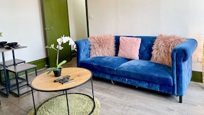Un salon avec un canapé bleu, une table basse ronde et une porte verte.