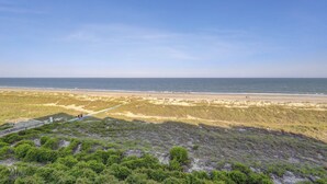 Una playa con cielo despejado, orilla de arena y dunas.