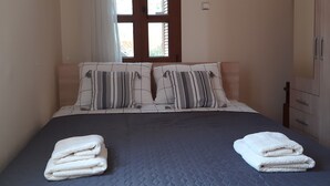Ein Schlafzimmer mit Bett, Kissen, einem Fenster und einem Kleiderschrank.