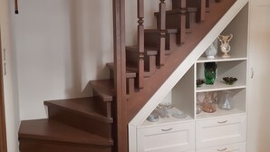 Eine Holztreppe mit einer weißen Wand und einem weißen Schrank darunter.