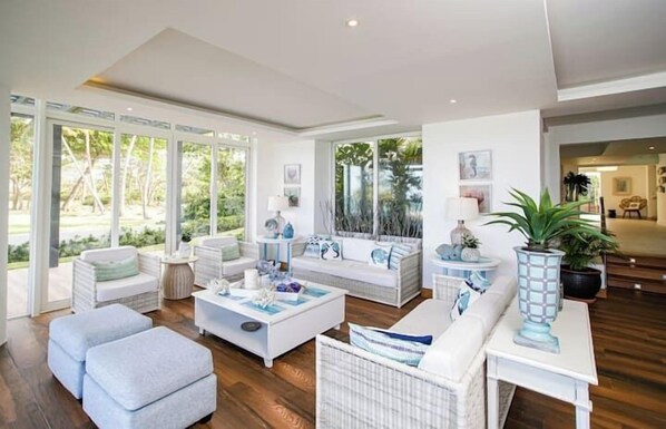 A modern living room with a large window, white furniture, and a potted plant.