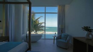 Habitación de hotel con un ventanal que ofrece vistas a la playa y al océano.