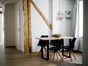 A dining area with a wooden table, black chairs, and a hanging light fixture.