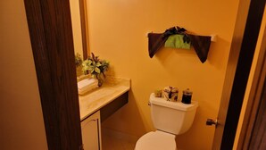 A small bathroom with a toilet, a sink, and a mirror. There is a plant on the sink counter and a trash can next to the toilet. - Stylish two bedroom Condo (Milwaukee)